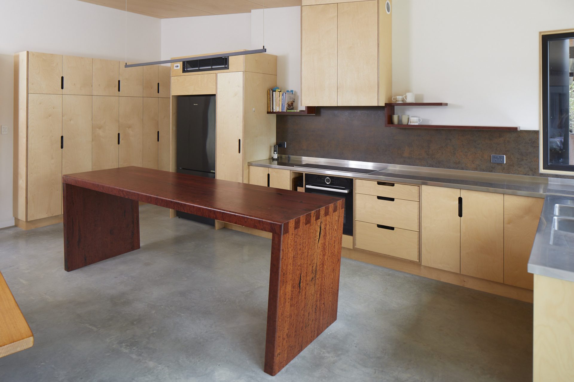 Redgum island bench in plywood kitchen with custom stainless steel bench top.